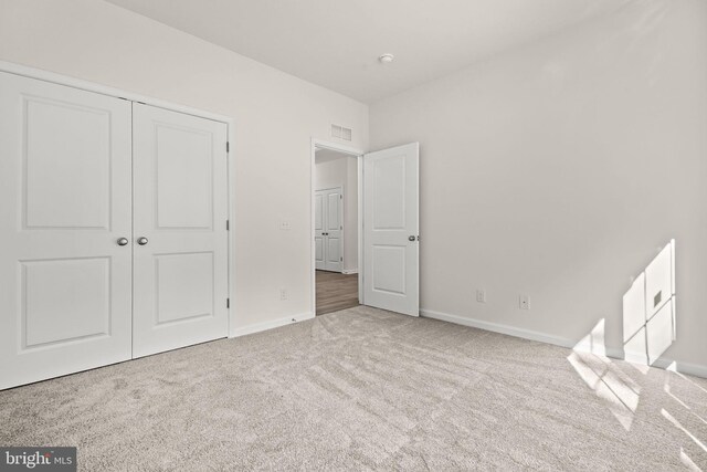 unfurnished bedroom featuring light carpet and a closet