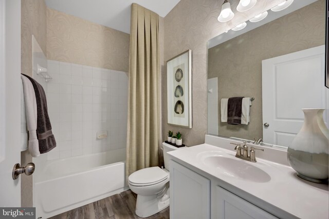 full bathroom featuring hardwood / wood-style flooring, shower / tub combo with curtain, vanity, and toilet