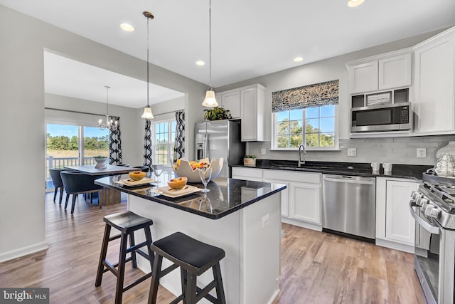 kitchen with white cabinets, a center island, stainless steel appliances, and hanging light fixtures