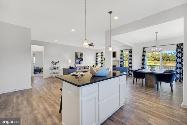 kitchen featuring ceiling fan with notable chandelier, light wood-type flooring, decorative light fixtures, a kitchen island, and white cabinetry