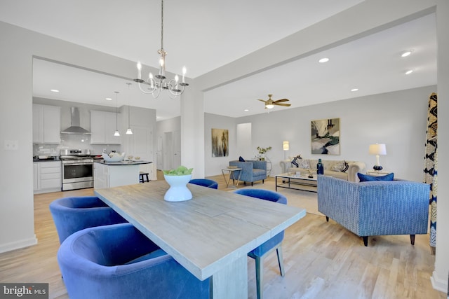 dining area featuring ceiling fan with notable chandelier and light hardwood / wood-style flooring