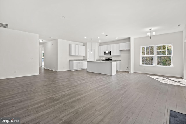 unfurnished living room featuring hardwood / wood-style flooring and a chandelier