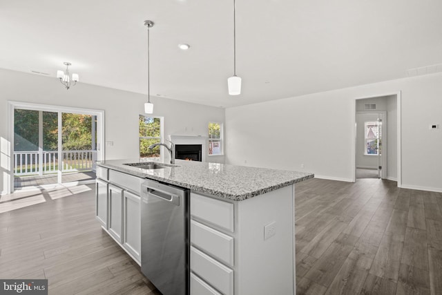 kitchen featuring white cabinetry, dishwasher, sink, hanging light fixtures, and light stone counters