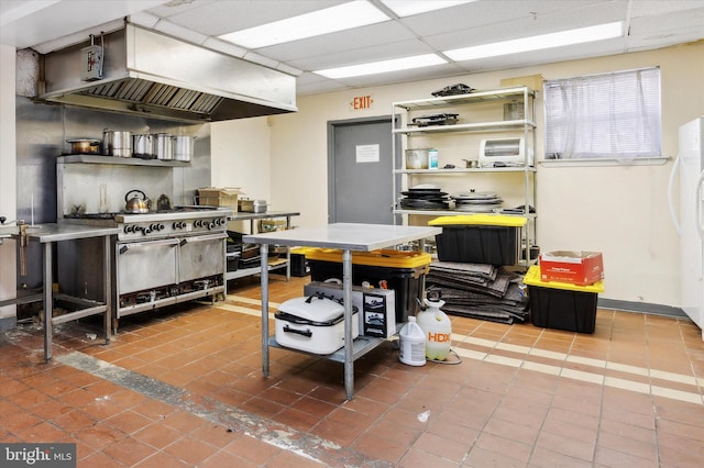 interior space with tile floors, premium range hood, stainless steel stove, and a drop ceiling