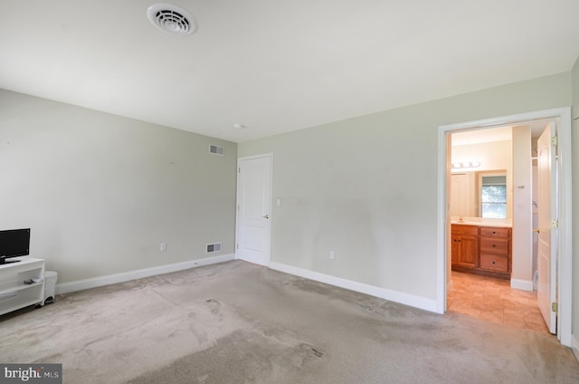 unfurnished bedroom with connected bathroom and light colored carpet