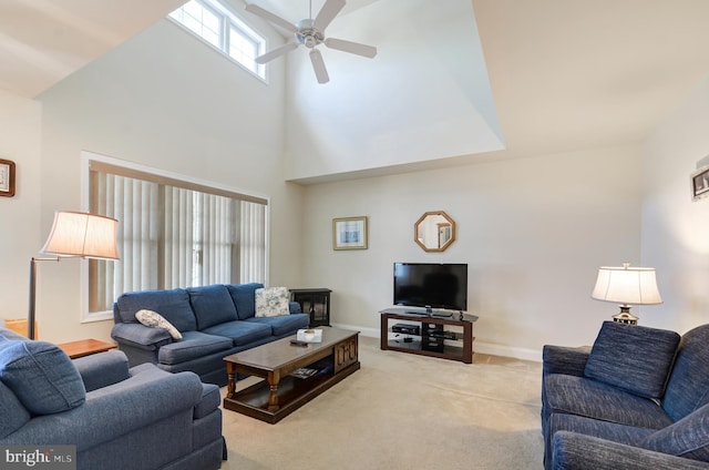 carpeted living room featuring ceiling fan and a towering ceiling