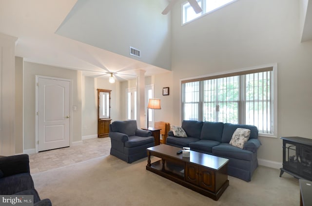 carpeted living room featuring a wood stove and a towering ceiling