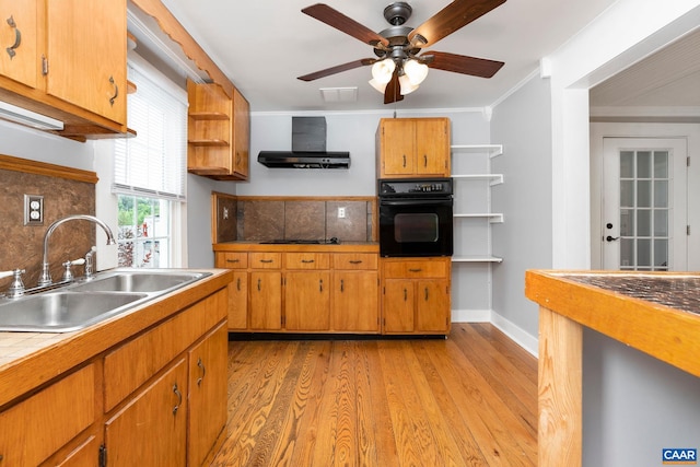 kitchen featuring ornamental molding, wall chimney range hood, sink, black appliances, and light hardwood / wood-style floors