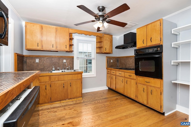 kitchen featuring sink, ventilation hood, crown molding, black appliances, and light wood-type flooring