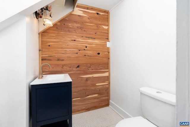 bathroom with vanity, toilet, and wooden walls