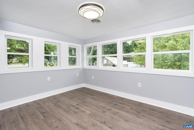 empty room featuring dark wood-type flooring and a healthy amount of sunlight