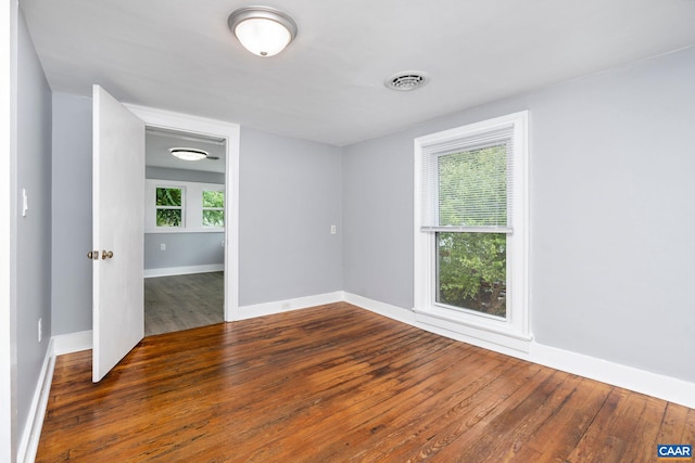 empty room with a wealth of natural light and dark hardwood / wood-style floors