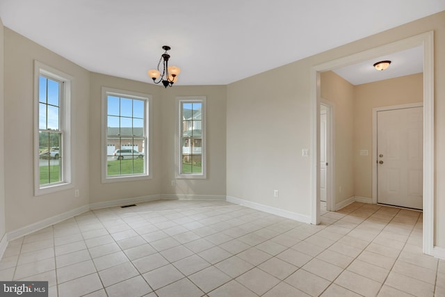 unfurnished room featuring light tile patterned floors and a notable chandelier