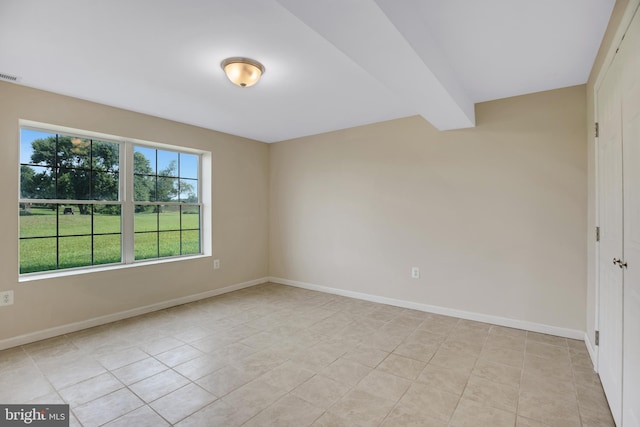 unfurnished room with beamed ceiling and light tile patterned floors