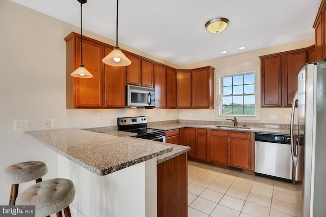 kitchen with sink, hanging light fixtures, stainless steel appliances, kitchen peninsula, and a breakfast bar area