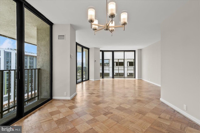 unfurnished room with light parquet floors, a healthy amount of sunlight, a wall of windows, and an inviting chandelier