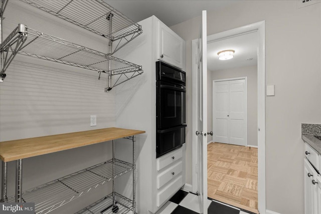 kitchen with white cabinets, light parquet floors, and oven