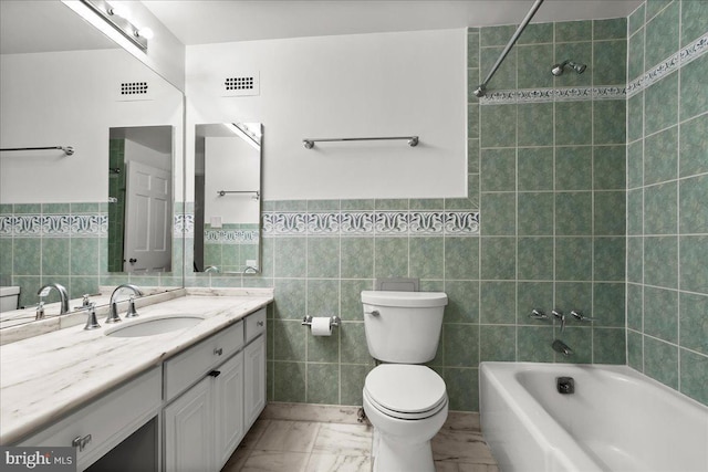 full bathroom featuring toilet, vanity, tile walls, and tiled shower / bath