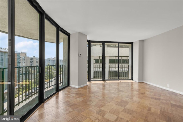 unfurnished room with light parquet flooring and a wall of windows