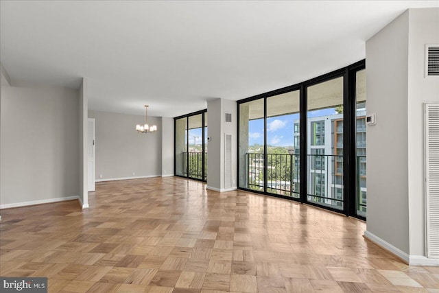 empty room with a notable chandelier, floor to ceiling windows, and light parquet floors