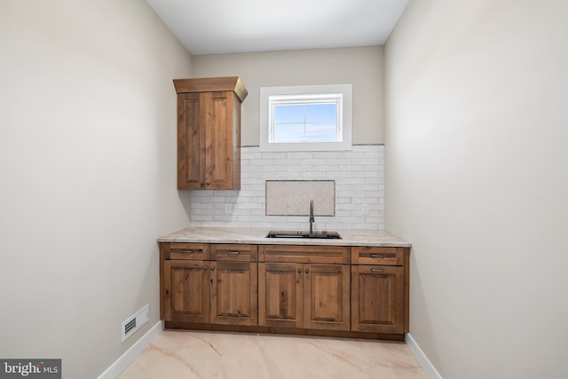 interior space with sink, light tile flooring, and backsplash