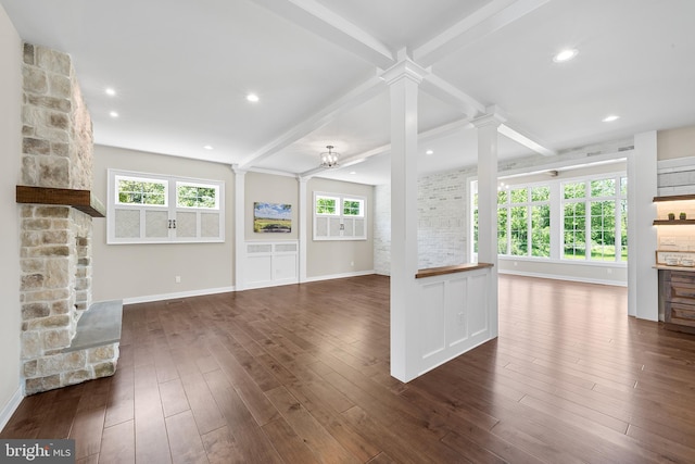 unfurnished living room featuring dark hardwood / wood-style floors, beam ceiling, and decorative columns