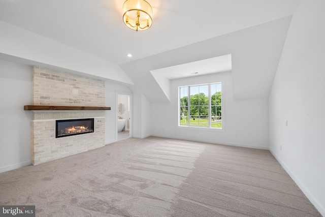 unfurnished living room featuring carpet, a fireplace, lofted ceiling, and brick wall