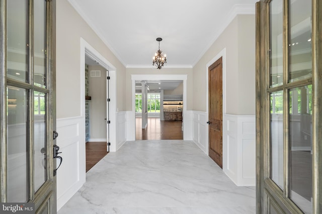 interior space featuring tile flooring, ornamental molding, and an inviting chandelier