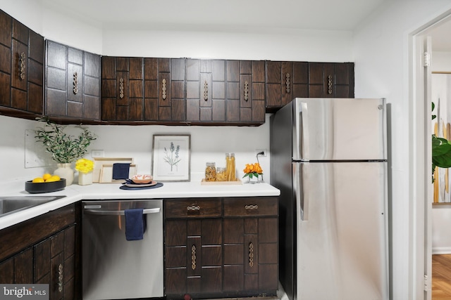 kitchen with appliances with stainless steel finishes, hardwood / wood-style floors, and dark brown cabinetry