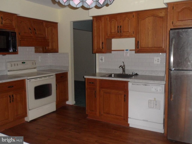 kitchen with sink, dark hardwood / wood-style flooring, white appliances, and tasteful backsplash