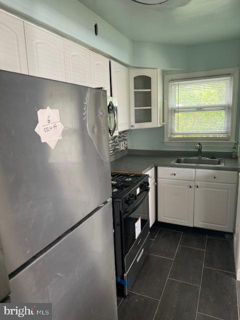 kitchen featuring stainless steel refrigerator, black gas stove, white cabinets, and sink