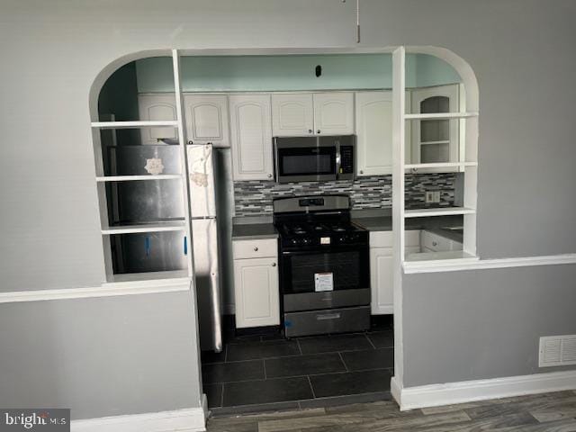 kitchen with backsplash, white cabinets, and appliances with stainless steel finishes