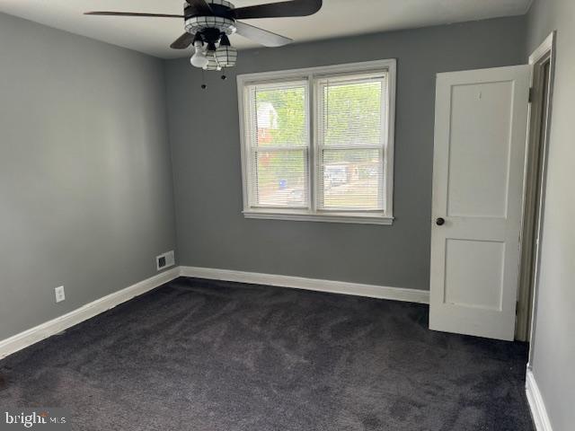 unfurnished room featuring dark colored carpet and ceiling fan