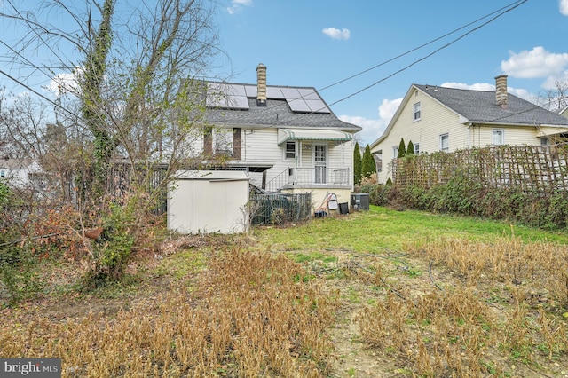 back of house featuring solar panels and central AC unit