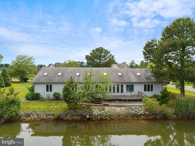 back of property featuring a yard and a deck with water view