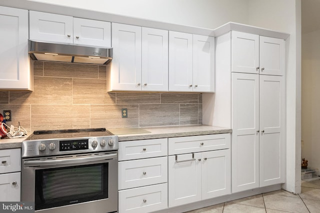 kitchen featuring electric stove, tasteful backsplash, white cabinetry, and light tile floors