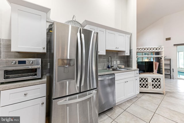 kitchen featuring stainless steel appliances, white cabinets, backsplash, sink, and light tile floors