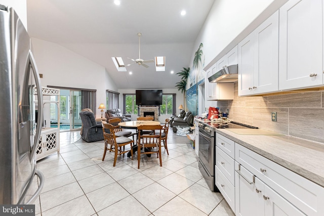 kitchen featuring ceiling fan, tasteful backsplash, stainless steel appliances, high vaulted ceiling, and white cabinetry