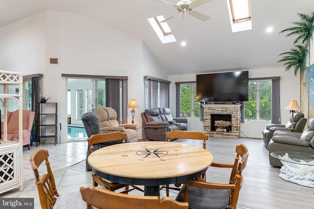 dining space featuring ceiling fan, a healthy amount of sunlight, a fireplace, and a skylight