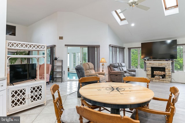 tiled dining space with a skylight, ceiling fan, a fireplace, and a wealth of natural light