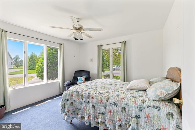 carpeted bedroom with ceiling fan and multiple windows