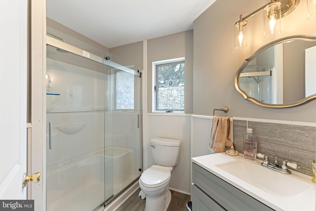 bathroom with wood-type flooring, a shower with shower door, toilet, and vanity