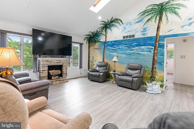 living room with a stone fireplace, hardwood / wood-style floors, and a skylight