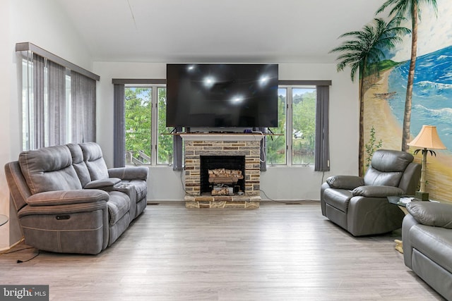 living room with a stone fireplace and light hardwood / wood-style floors