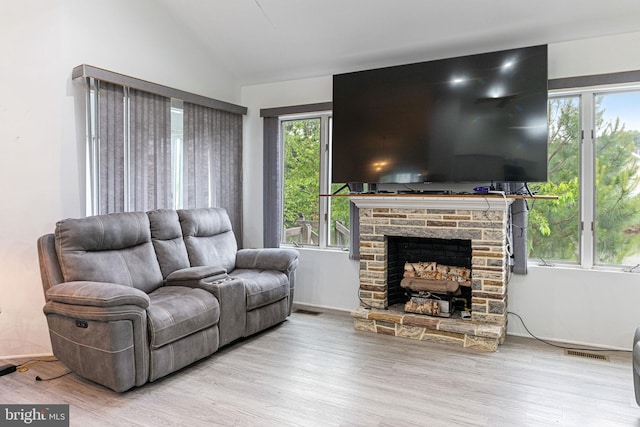 living room with lofted ceiling, light wood-type flooring, and a fireplace