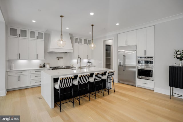 7013 Raleigh Rd, Annandale, VA 22003 - kitchen with light wood finished floors, custom exhaust hood, stainless steel appliances, and a sink