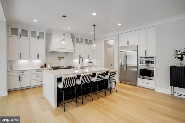 7013 Raleigh Rd, Annandale, VA 22003 - kitchen featuring light wood-type flooring, custom exhaust hood, a sink, and appliances with stainless steel finishes