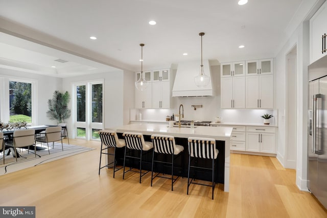 7013 Raleigh Rd, Annandale, VA 22003 - kitchen with light countertops, high end fridge, light wood-type flooring, glass insert cabinets, and custom exhaust hood