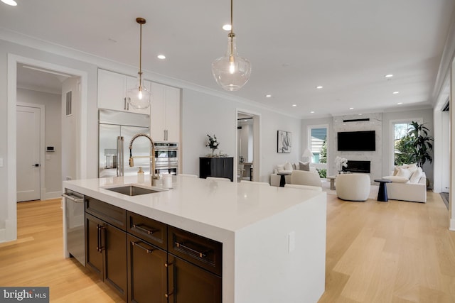 7013 Raleigh Rd, Annandale, VA 22003 - kitchen with dark brown cabinets, a sink, light wood-style floors, white cabinets, and appliances with stainless steel finishes