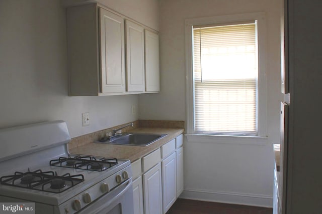 kitchen featuring white cabinets, white gas range, a healthy amount of sunlight, and sink